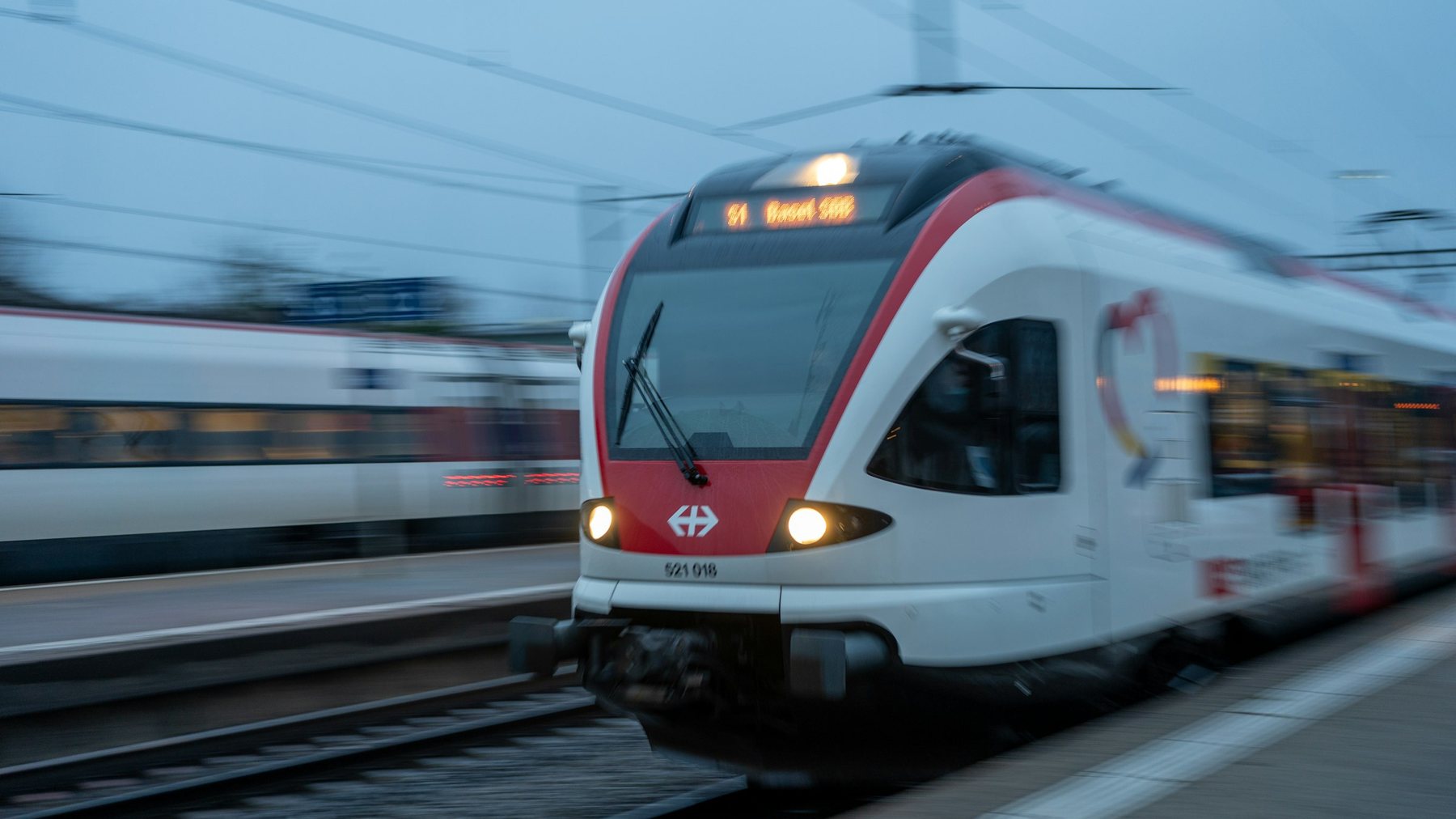 Ein weiss-roter SBB-Regionalzug fährt in einen Bahnhof ein.